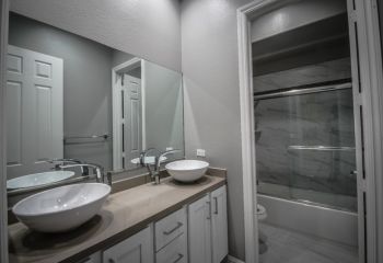Modern bathroom remodel featuring floating vanity with vessel sinks, minimalist fixtures, and elegant gray color palette